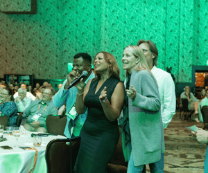 three people singing at a franchise convention