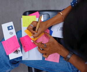 woman writing on a sticky note during a leadership meeting